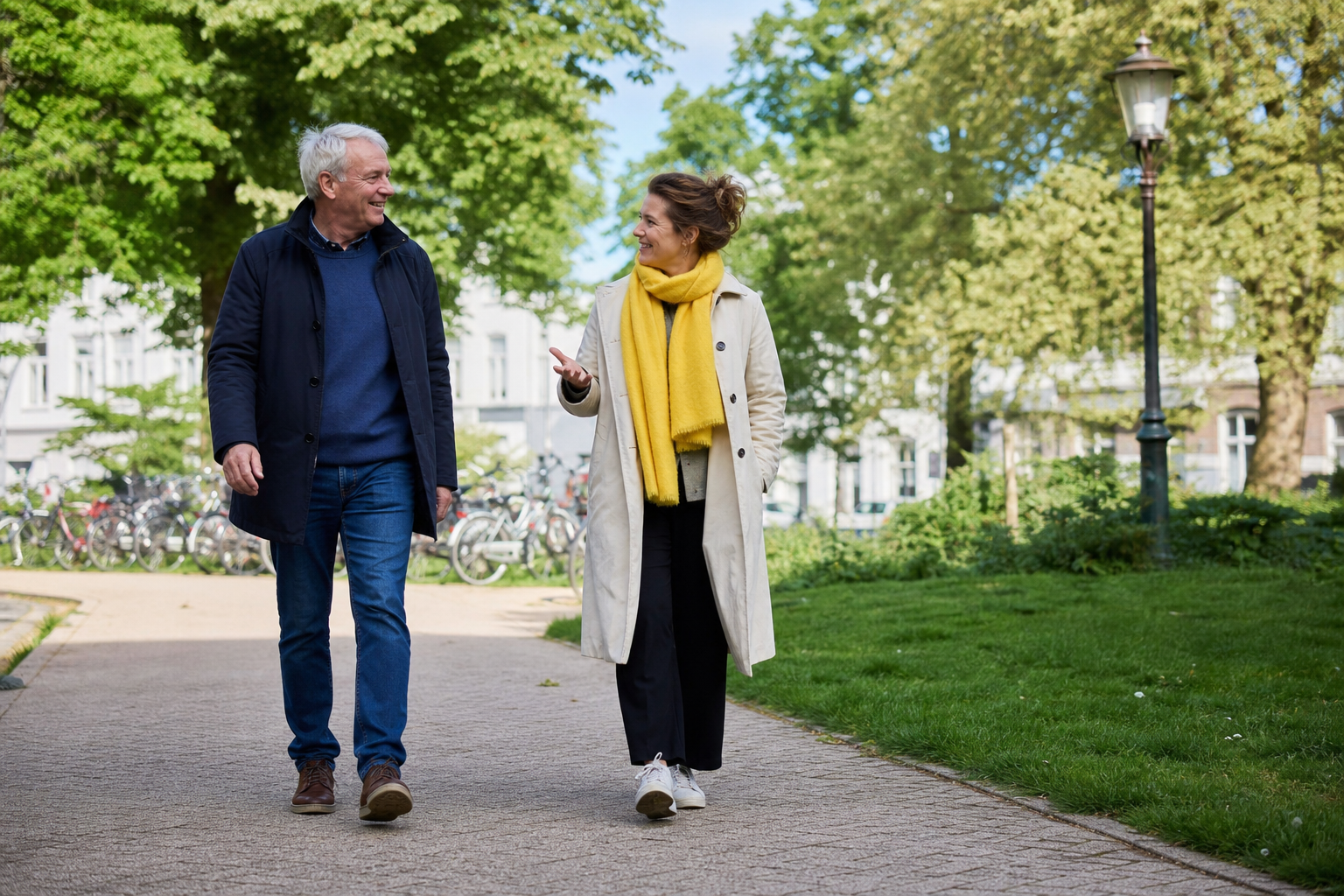 Twee volwassenen wandelen ontspannen samen over een groen pad in de stad